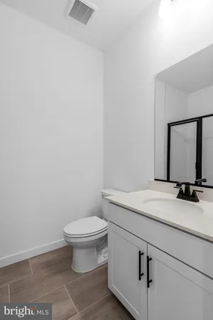 a bathroom with a granite countertop toilet sink and mirror