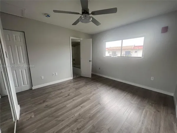 an empty room with wooden floor fan and windows