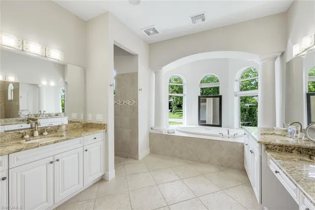 a spacious bathroom with a granite countertop tub a sink and a large mirror