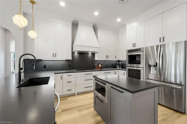 a kitchen with granite countertop a sink stainless steel appliances and white cabinets