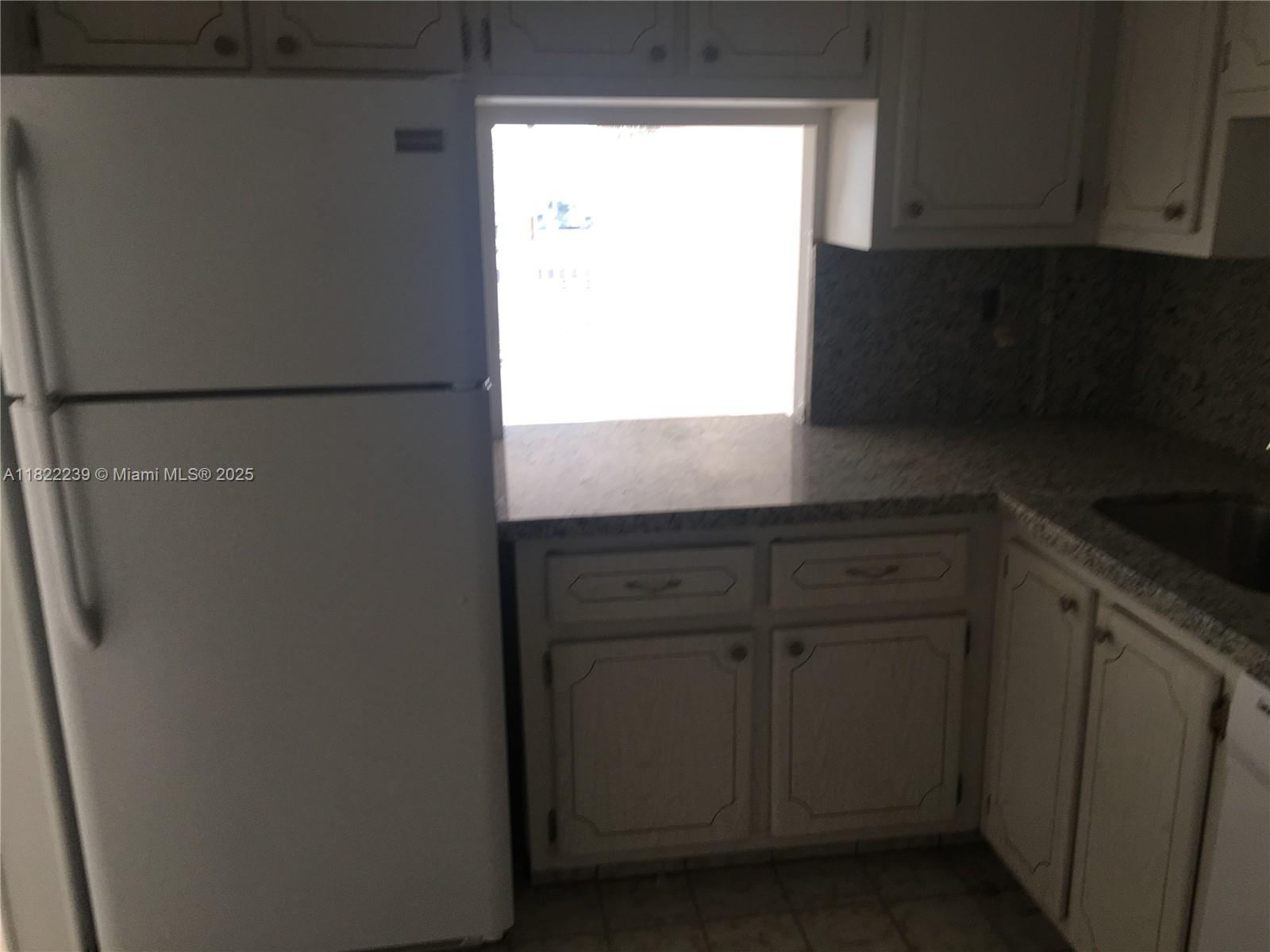 2200 East Hallandale Beach Boulevard, Unit 708 Hallandale Beach, FL 33009 - Photo 5 of 14 a kitchen with a white cabinets and a refrigerator