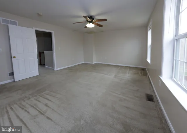 an empty room with a window and a ceiling fan