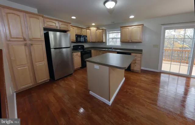 a kitchen with stainless steel appliances granite countertop a refrigerator a sink a stove a microwave and wooden floor