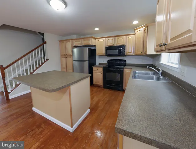 a kitchen with stainless steel appliances granite countertop a refrigerator a stove and a sink with wooden floor