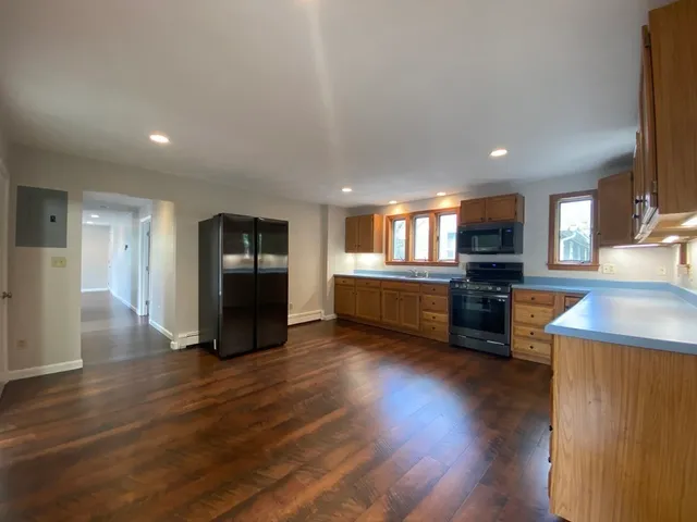 a kitchen with stainless steel appliances kitchen island granite countertop a stove top oven a sink and a refrigerator