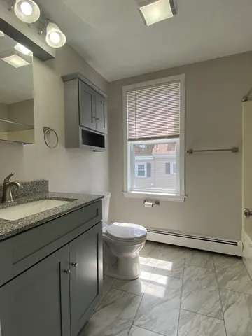 a bathroom with a granite countertop sink a toilet and a mirror