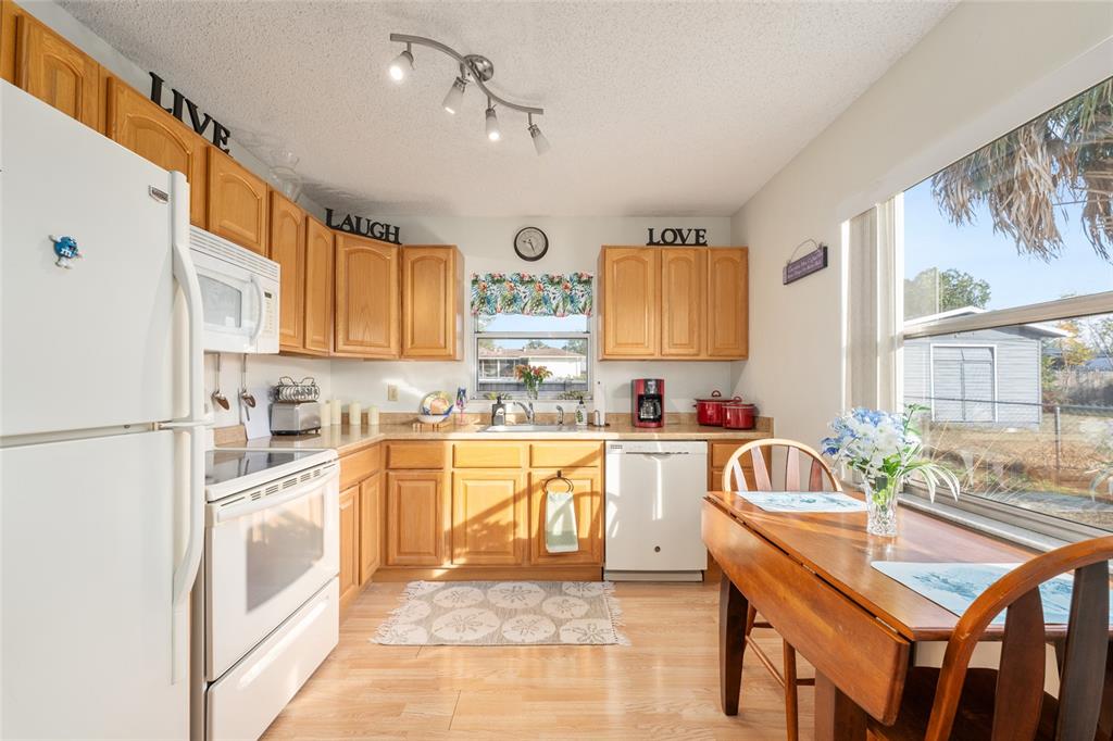 21373 Southwest Raintree Street Dunnellon, FL 34431 - Photo 22 of 39 a large white kitchen with stainless steel appliances granite countertop a stove a sink dishwasher and a refrigerator with white cabinets