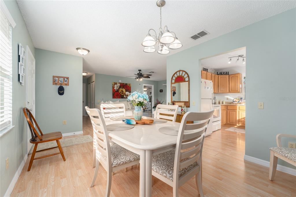 21373 Southwest Raintree Street Dunnellon, FL 34431 - Photo 10 of 39 a dining room with wooden floor a chandelier a wooden table and chairs
