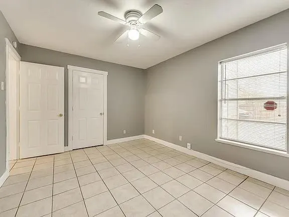 an empty room with windows and fan