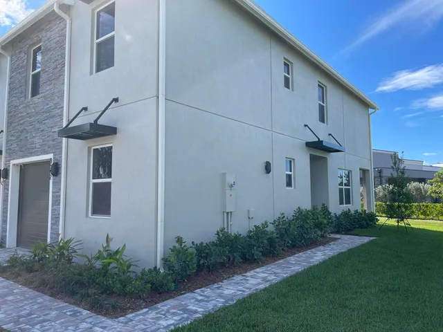 a view of a white house next to a yard