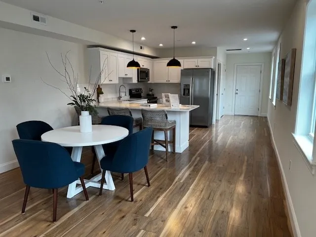 a kitchen with kitchen island a dining table chairs stainless steel appliances and cabinets