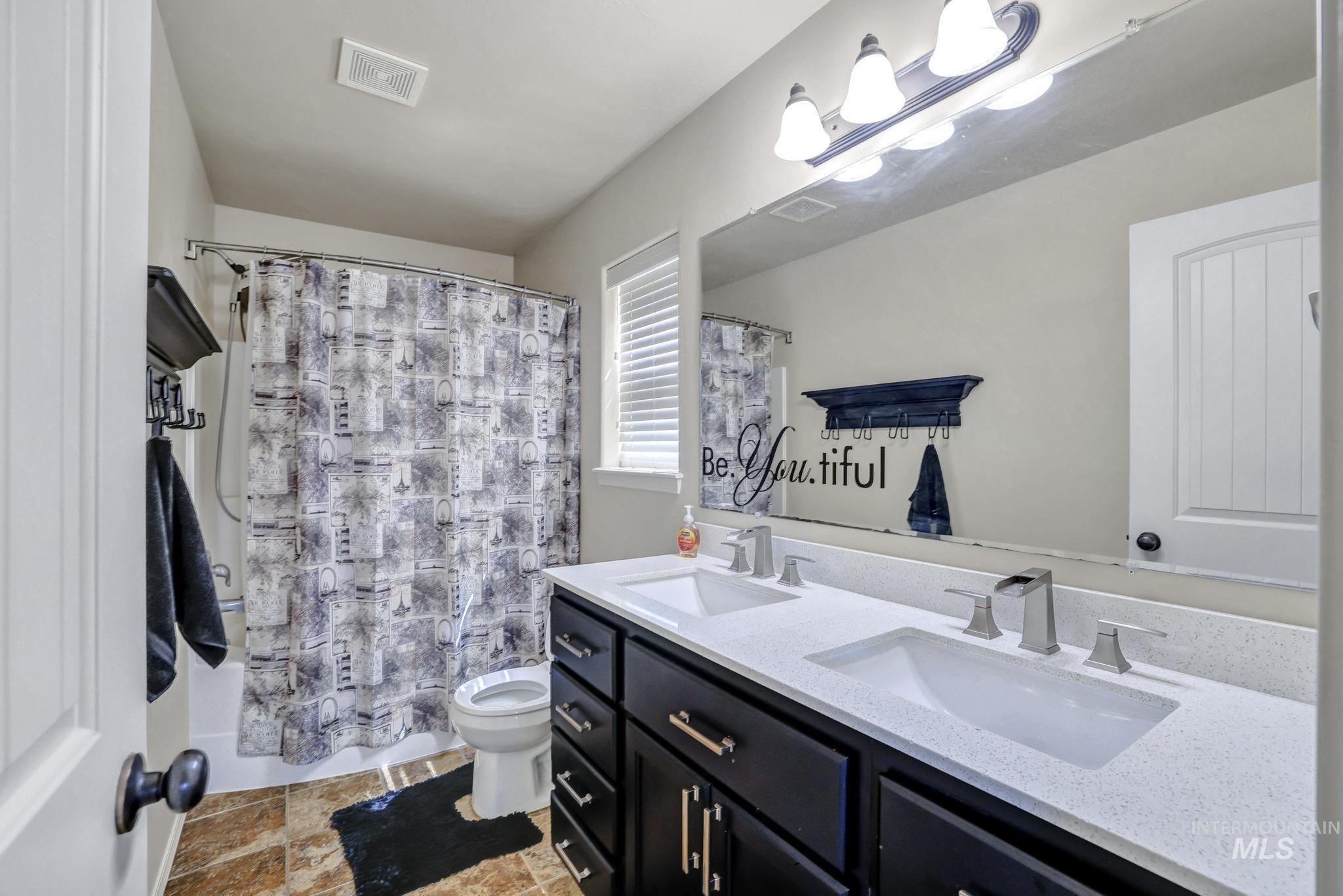 446 Noble Street Twin Falls, ID 83301 - Photo 21 of 42 Bathroom featuring a dual vanity with a light-toned countertop, black cabinetry, and brushed nickel fixtures