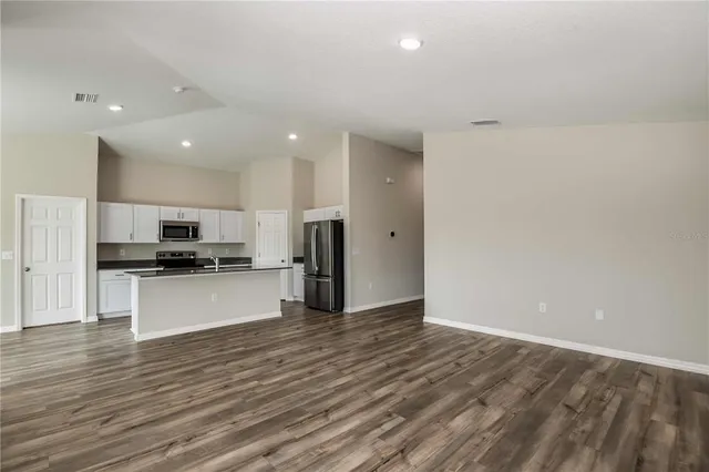 a view of kitchen with stainless steel appliances wooden floor and large window