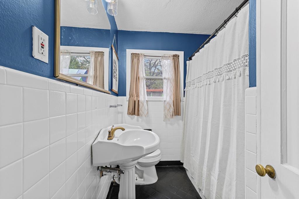 1208 Sunset Street Waco, TX 76710 - Photo 10 of 24 a bathroom with a sink a toilet and a mirror