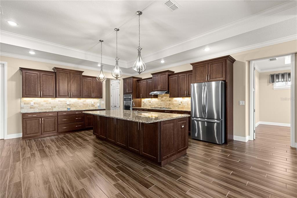 9460 Southwest 86th Place Ocala, FL 34481 - Photo 14 of 86 a kitchen with stainless steel appliances granite countertop a refrigerator a sink dishwasher a oven and a dining table with wooden floor