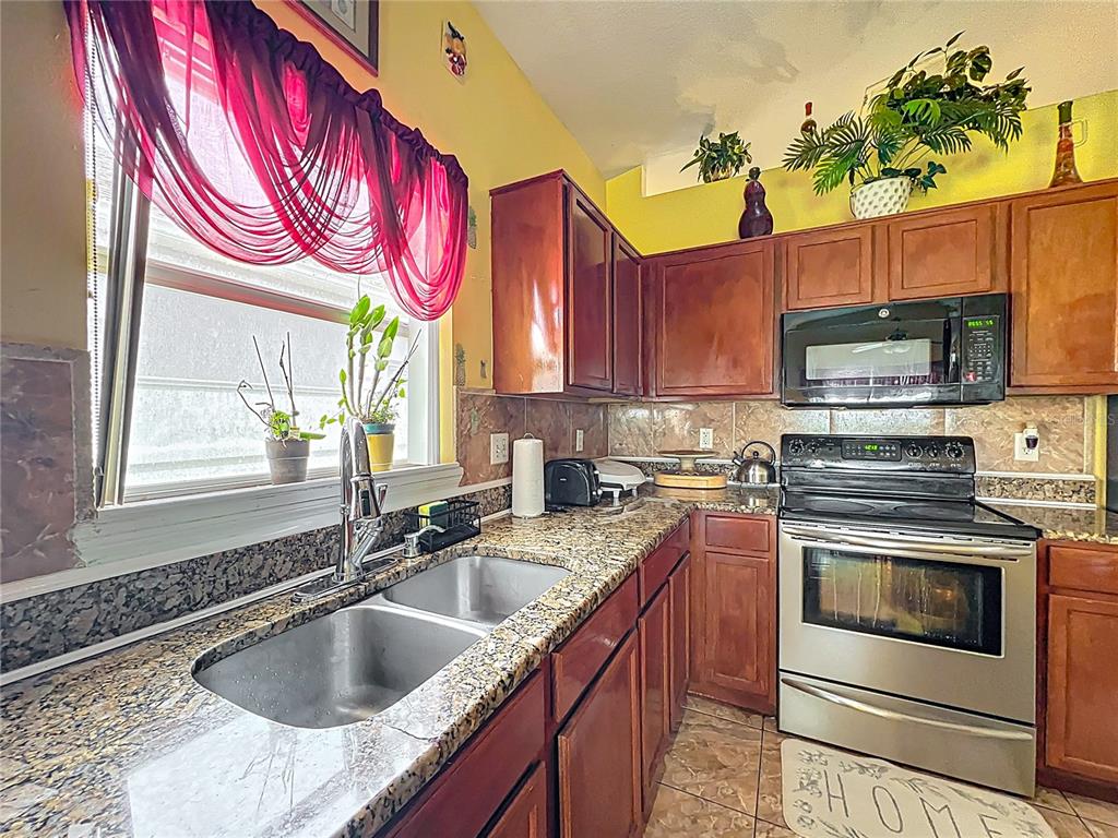 7939 Riffle Lane Orlando, FL 32818 - Photo 10 of 52 a kitchen with stainless steel appliances granite countertop a sink a stove and a microwave