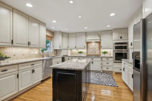 a kitchen with granite countertop stainless steel appliances white cabinets and a window