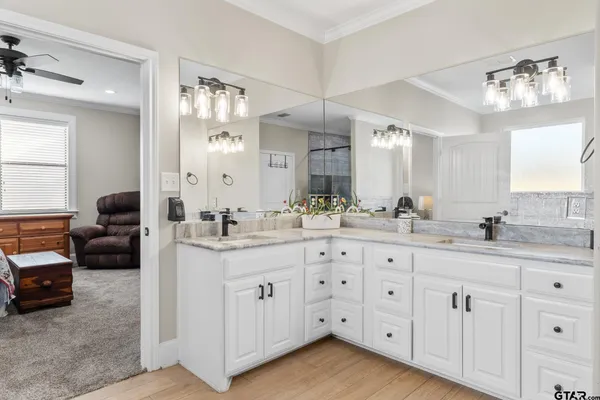 a spacious bathroom with double sink a mirror a window and a bathtub