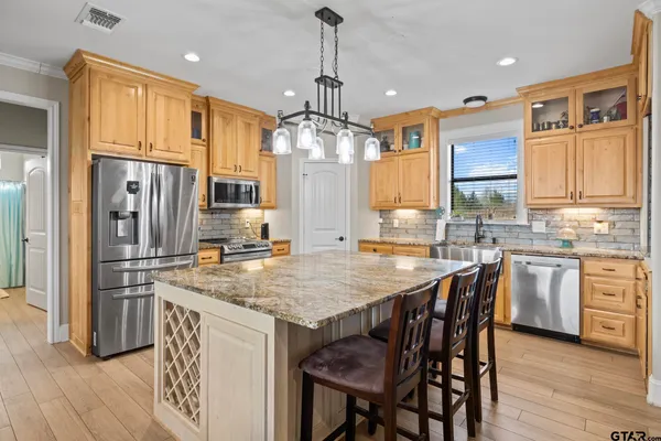 a kitchen with stainless steel appliances granite countertop a kitchen island hardwood floor and a sink