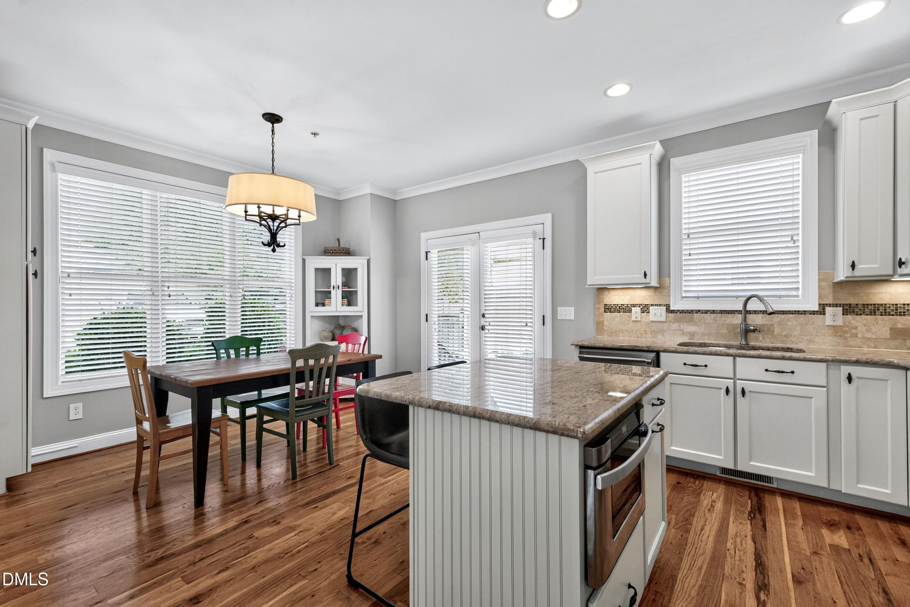2745 Oberlin Road, Unit 103 Raleigh, NC 27608 - Photo 12 of 23 a kitchen with granite countertop a stove a sink a dining table and chairs with wooden floor