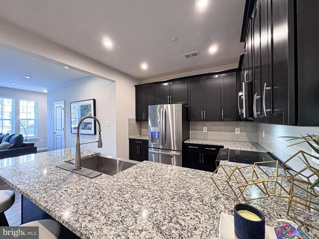 a kitchen with stainless steel appliances kitchen island granite countertop a refrigerator and a stove top oven