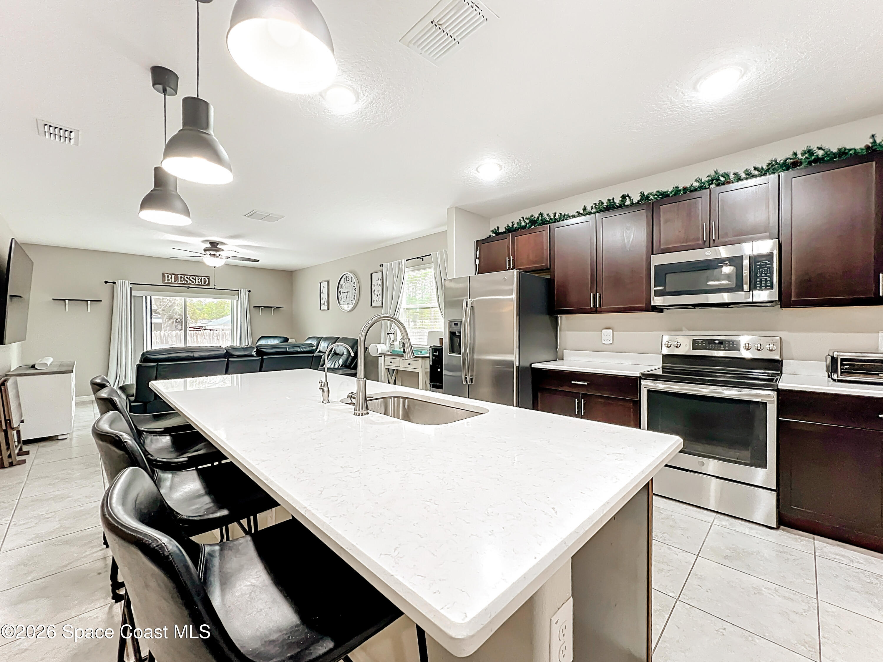 415 Scodella Street Southwest Palm Bay, FL 32908 - Photo 16 of 54 an open kitchen with kitchen island white cabinets and stainless steel appliances