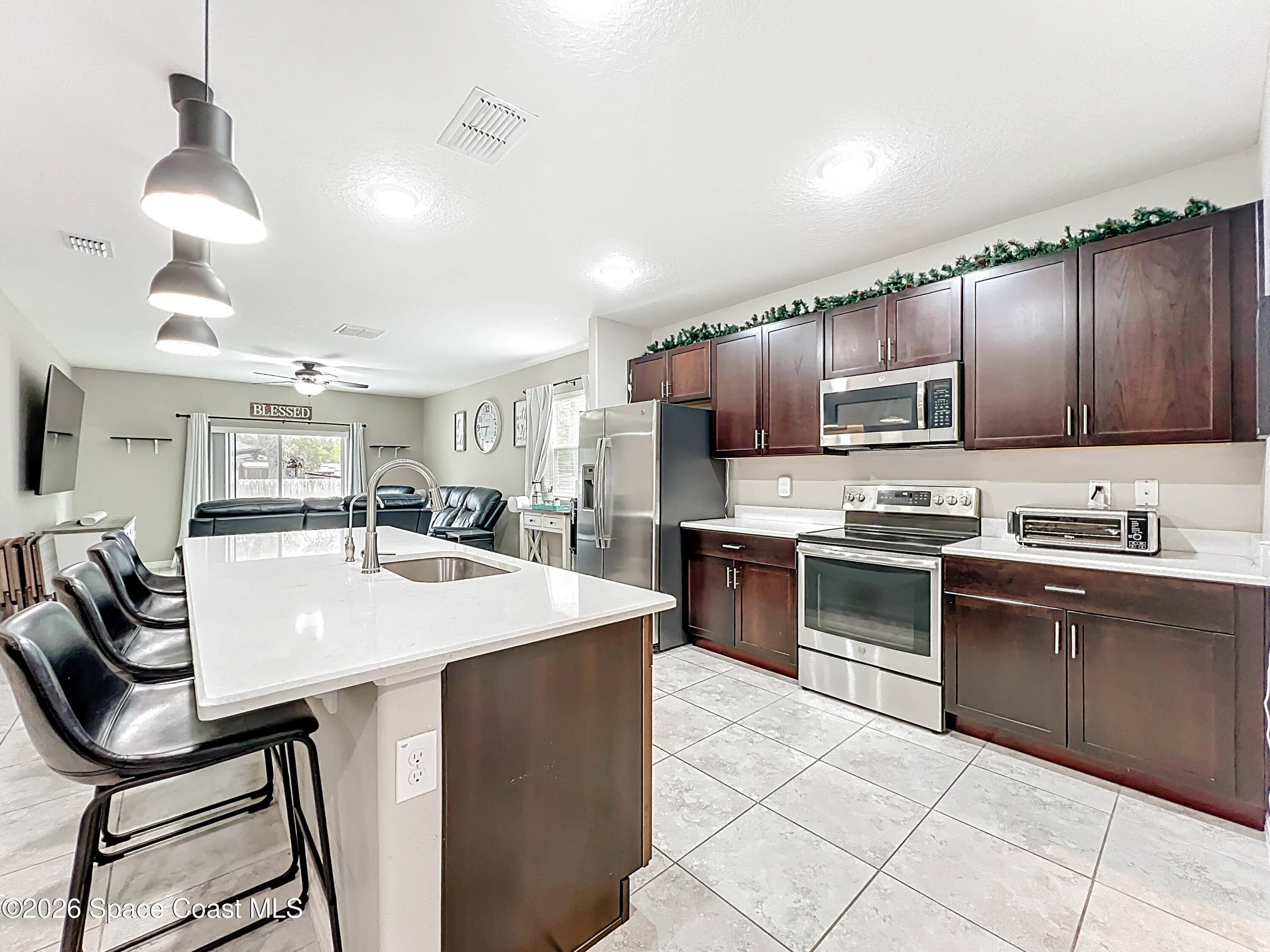 415 Scodella Street Southwest Palm Bay, FL 32908 - Photo 17 of 54 a kitchen with kitchen island granite countertop a stove cabinets and refrigerator