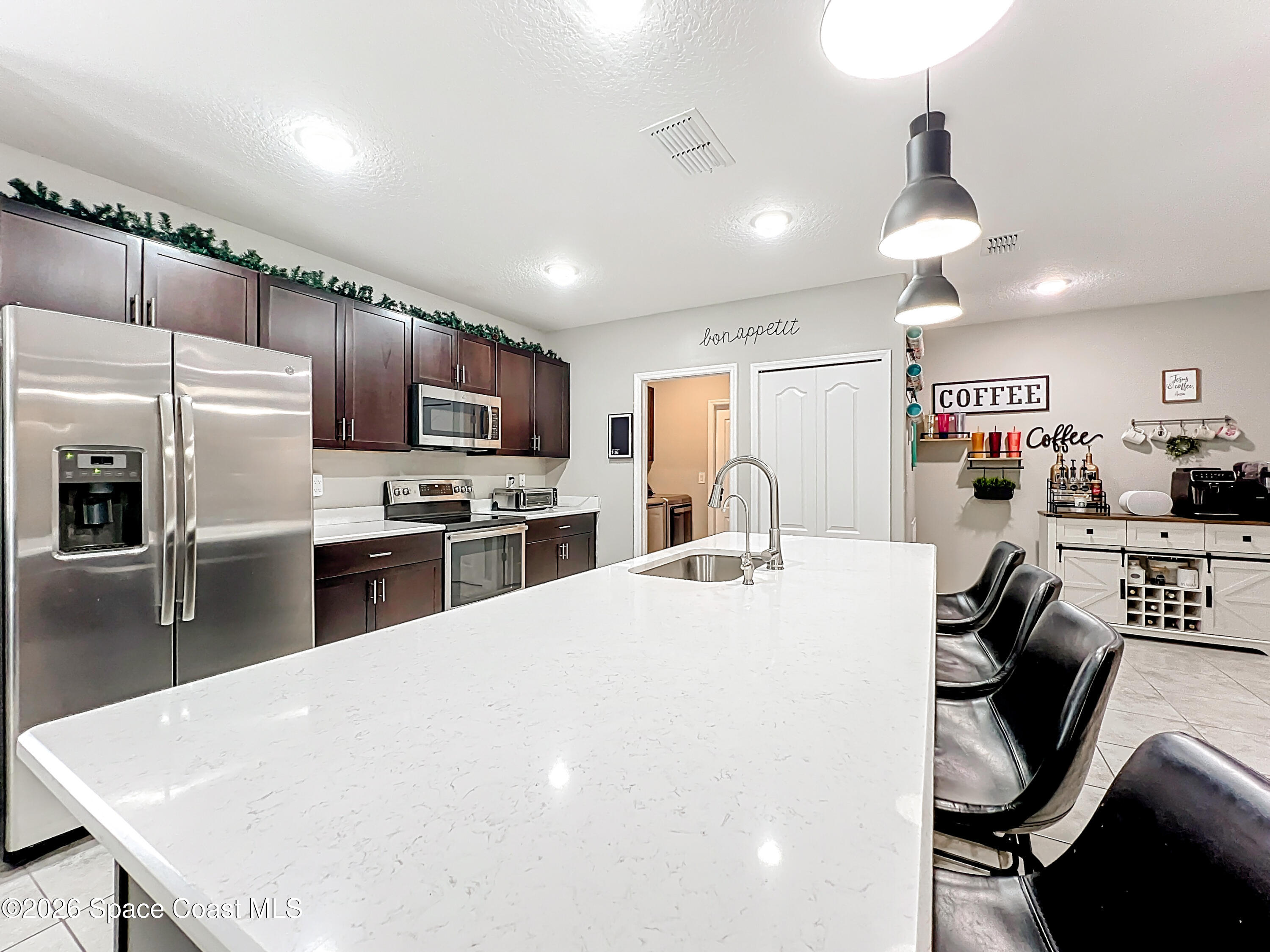 415 Scodella Street Southwest Palm Bay, FL 32908 - Photo 24 of 54 a kitchen with stainless steel appliances a stove sink refrigerator dining table and chairs
