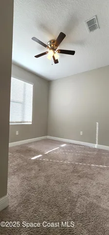 an empty room with windows and fan