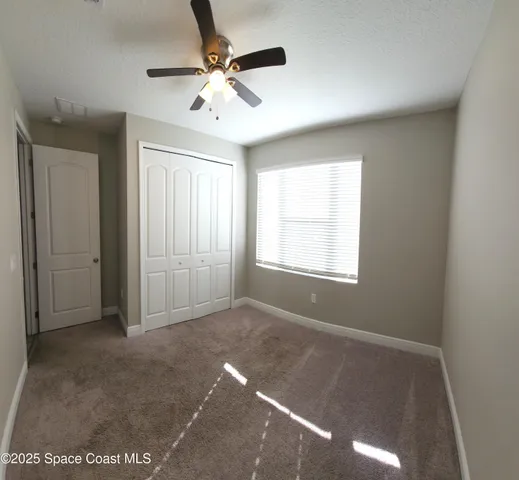 an empty room with windows and fan