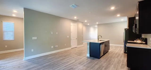 a kitchen with a refrigerator and a wooden floor