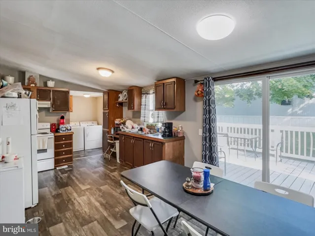 a kitchen with granite countertop a refrigerator a stove and a sink with wooden floor