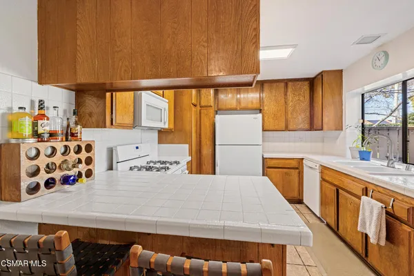 a kitchen with stainless steel appliances a sink a stove a refrigerator white cabinets and wooden floor