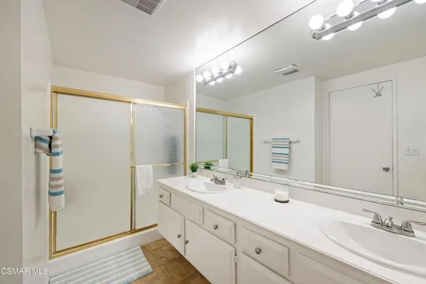 a bathroom with a double vanity sink a mirror and a shower