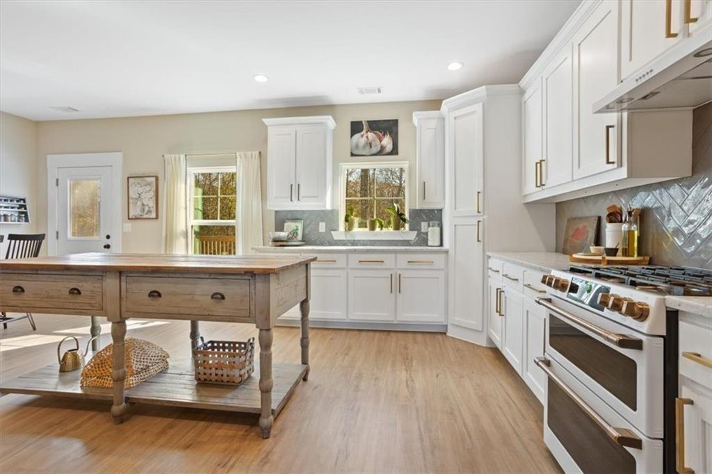 14402 Fincher Road Ball Ground, GA 30107 - Photo 20 of 55 a kitchen with stainless steel appliances granite countertop a stove a sink dishwasher and white cabinets with wooden floor