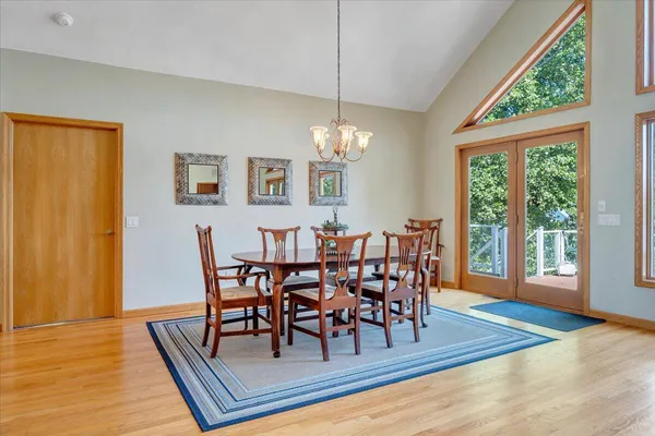 a kitchen with stainless steel appliances granite countertop a refrigerator a sink dishwasher a stove and a dining table with wooden floor