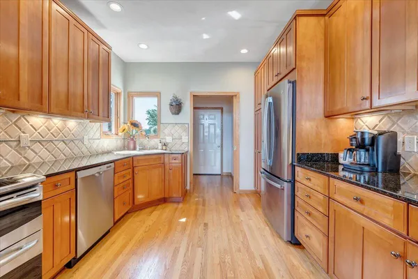 a view of a hallway with wooden floor and a bathroom