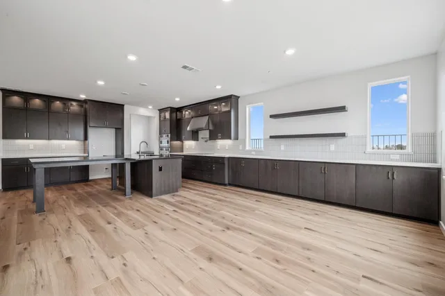 a large kitchen with stainless steel appliances kitchen island a large counter top and a stove top oven