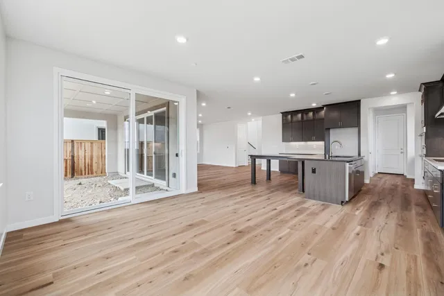 a large kitchen with stainless steel appliances kitchen island a large counter top a stove and a wooden floors