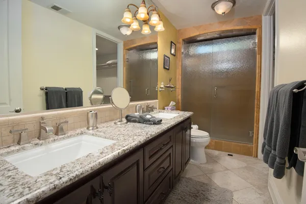 a bathroom with a granite countertop sink a mirror and a shower