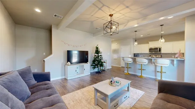 a living room with furniture kitchen view and a chandelier