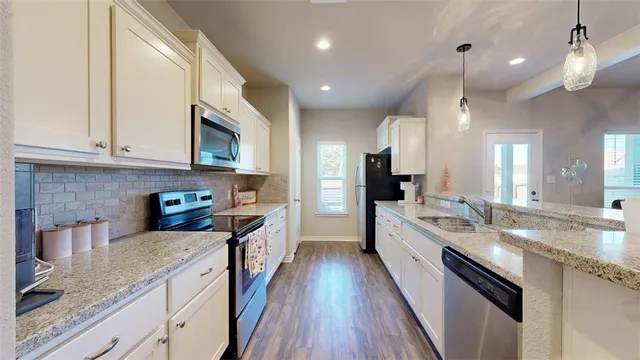 a large kitchen with stainless steel appliances granite countertop a lot of counter space a sink and dishwasher a stove top oven with wooden floor