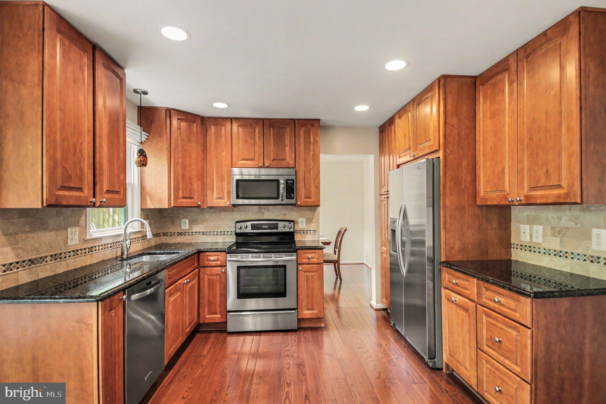 8309 Timber Brook Lane Springfield, VA 22153 - Photo 10 of 39 a kitchen with stainless steel appliances granite countertop a stove a sink dishwasher a refrigerator and cabinets with wooden floor
