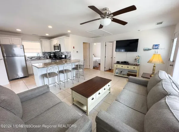a living room with furniture a flat screen tv and kitchen view