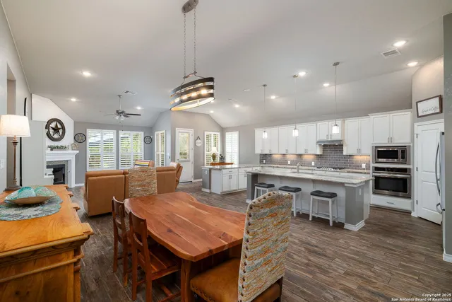 a dining room with stainless steel appliances furniture large window and wooden floor