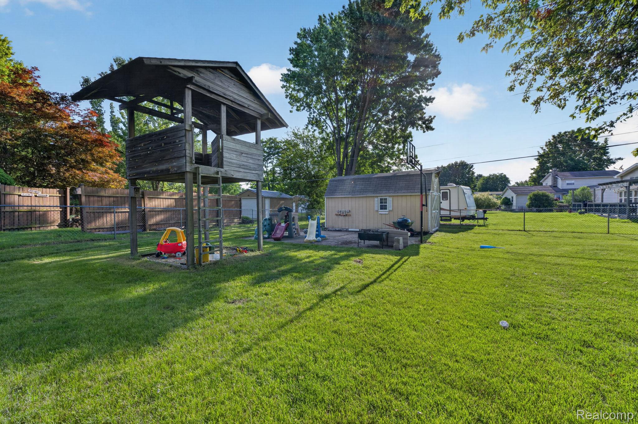5355 North Seymour Road Flushing, MI 48433 - Photo 36 of 46 Spacious backyard featuring a wood play structure, a detached storage shed, a privacy fence, and mature trees