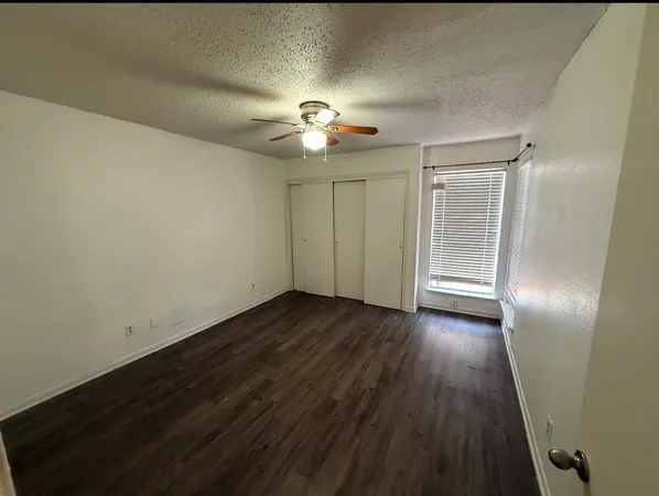 an empty room with wooden floor cabinet and windows