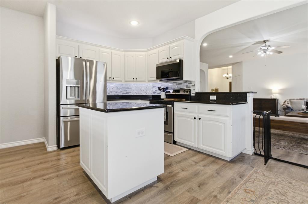 10928 Middleglen Road Fort Worth, TX 76052 - Photo 11 of 37 a kitchen with stainless steel appliances a stove top oven a sink a refrigerator white cabinets and wooden floor