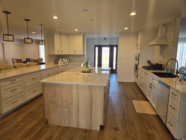 a kitchen with counter top space a sink wooden floor and kitchen view