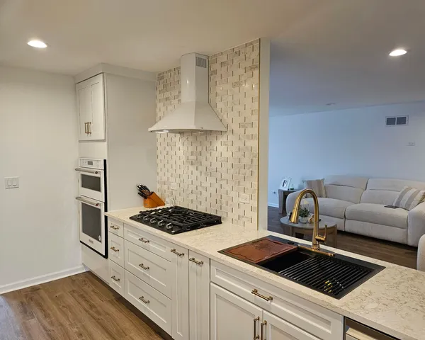 a kitchen with white cabinets a sink and a stove with wooden floor
